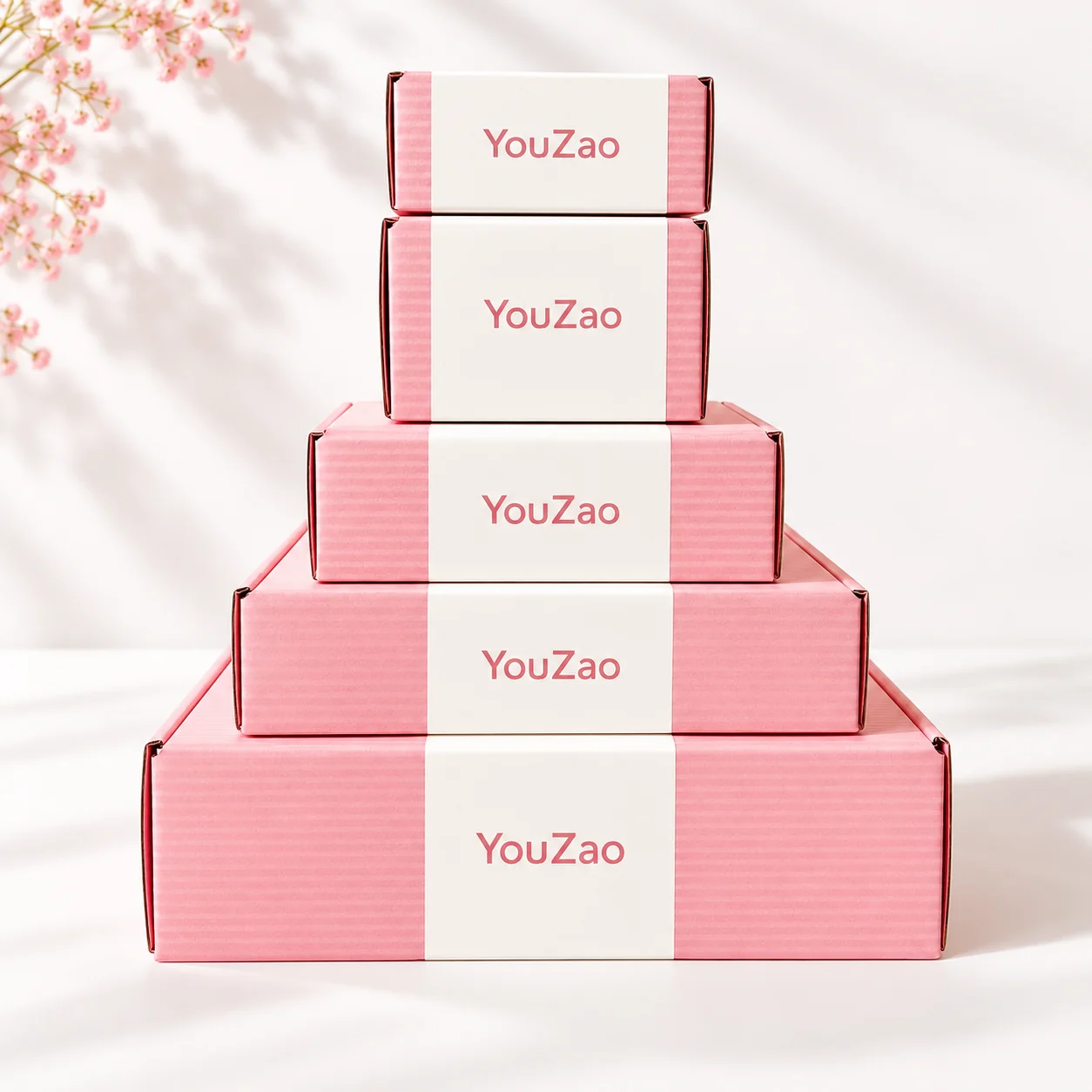 Five pink corrugated clothing packaging boxes stacked by size