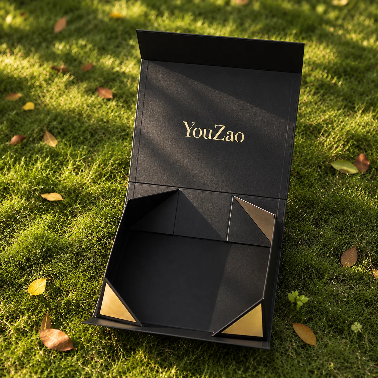 Open black gift box with gold accents and visible fold-in corner panels