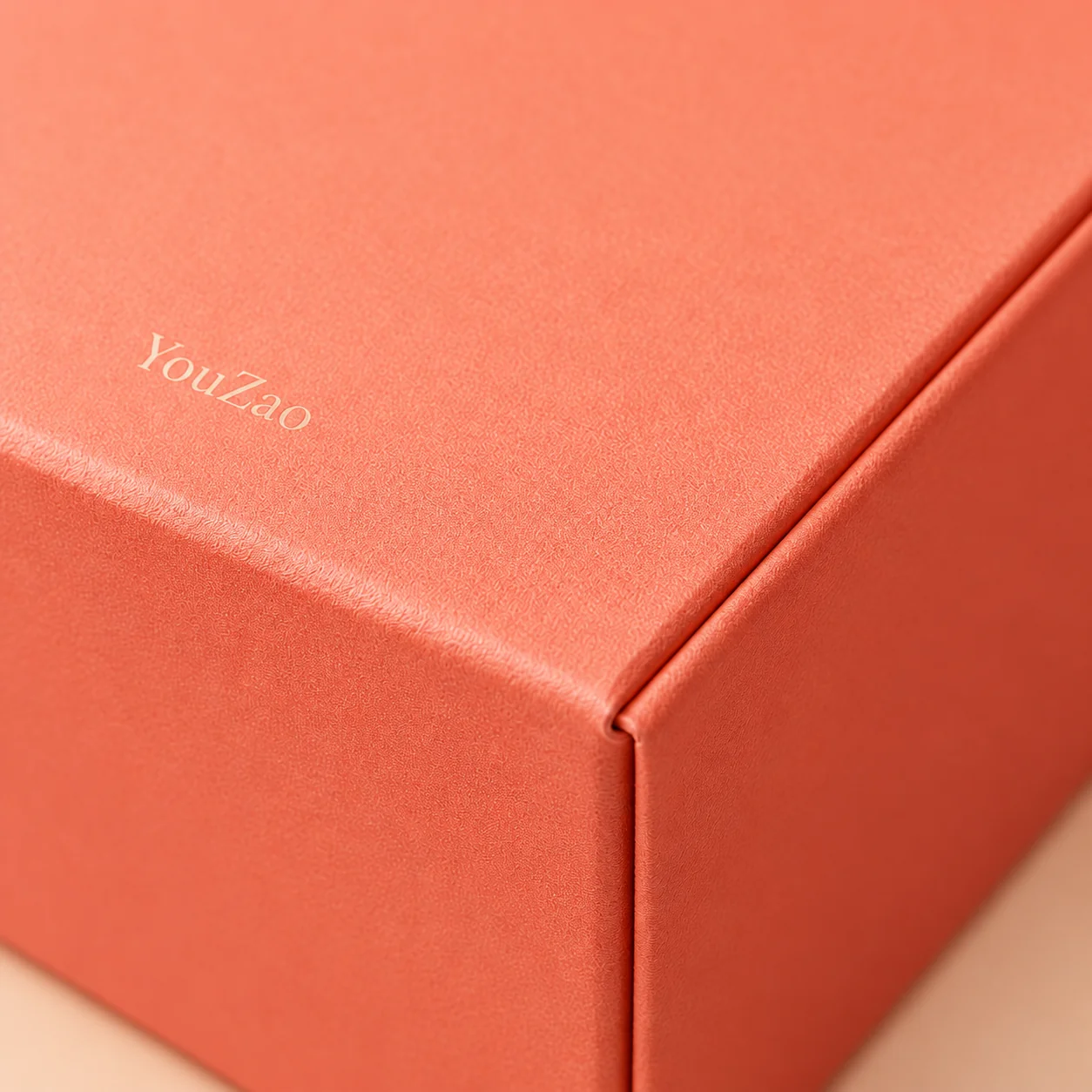Close-up of a coral paperboard box surface and folded lid edge